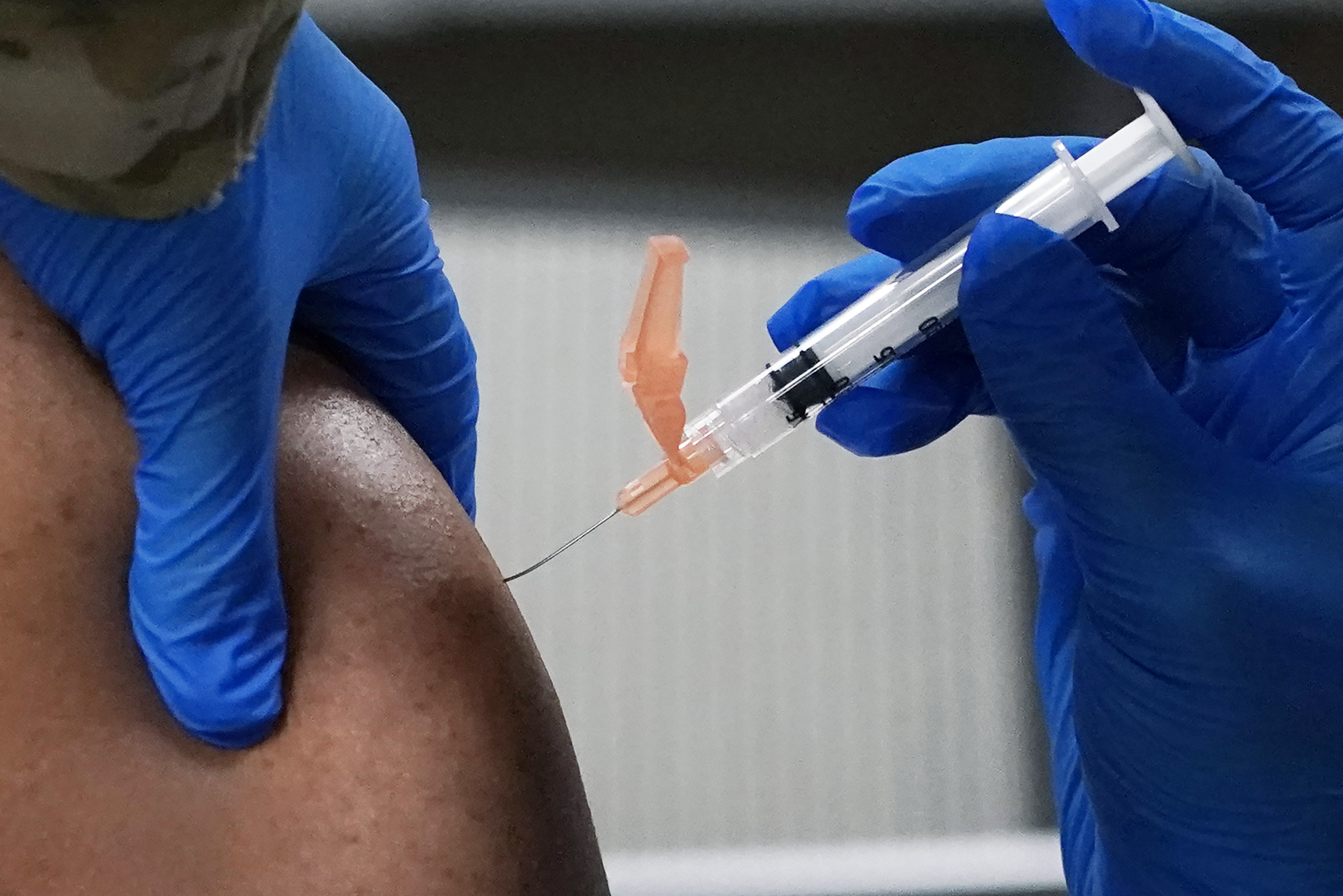 Senior Master Sgt. Hilton Washington of the Mississippi Air National Guard, left, receives a dose of the Moderna COVID-19 vaccine in his arm, by a fellow guard member, Wednesday, Dec. 23, 2020, in Flowood, Miss. One hundred doses of the vaccine were administered to both Mississippi Air and Army National Guard service members who serve as first responders and currently assist with the administering of the COVID-19 test at Mississippi Department of Health drive through community testing sites across the state. (AP Photo/Rogelio V. Solis)